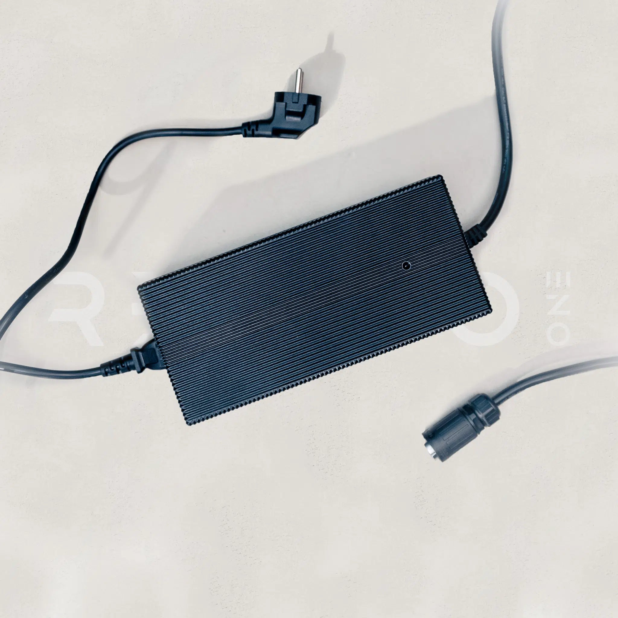 Black power adapter with multiple cables on a light gray background
