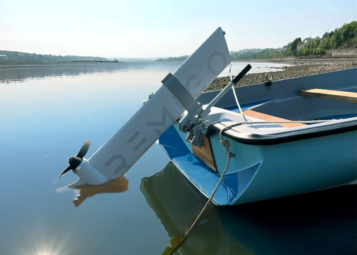 Small electric engine with a propeller attached to a blue boat on calm water