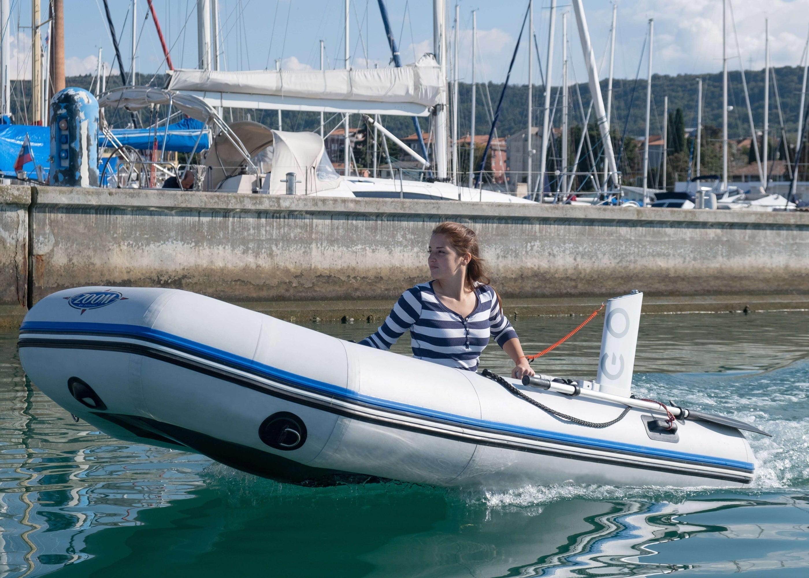 Inflatable dinghy powered by Remigo going in the harbor with a lady sitting in it 