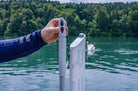Person holding a device - starting key on a dock with a lake and trees in the background
