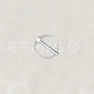 Silver ring with a stick-like object on a light gray background