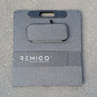 Gray solar panels cover with 'REMIGO' branding on a concrete surface