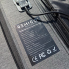 REMIGO electric outboard solar panel with charging cable and label on a gray surface
